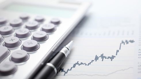 Calculator and ballpoint pen on stock market data chart